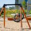 Fugleredehuske Lerk Enkel med svart nett og oransje ramme på lekeplass i sand.