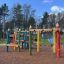Fargerik lekeplass med Floro klatrestativ i skog.