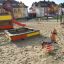 Sandkasse på lekeplass med husker og sklie i nærheten.