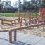 Seesaw Nature på en lekeplass omringet av andre trelekeapparater.
