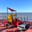 All Accessible Mars Playground med rød sklie og gul klatretavle på uteplass ved sjøen.