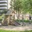 Lekeplass med Raw Nature Eco Tambora Lekeapparat omgitt av barn og voksne i en park.