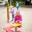 Barn leker ved Bord og Benk i en park.