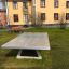 Bordtennisbord Betong Frittstående installert i en park foran en bygning.