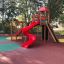 Rød lekeplass sklie og klatrestativ Twister i en park.