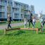 Barneleker på Balansebom i en park foran boligblokk.