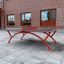Bordtennisbord Outdoor med rødt metallunderstell utenfor en murbygning.