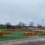 Moderne lekeplass InsideOut Treboks Lerk - Rett med grønt kunstgress og benker i tre.