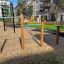 Utendørs lekeapparat Voltstang Trippel i en lekeplass, omgitt av bygninger.